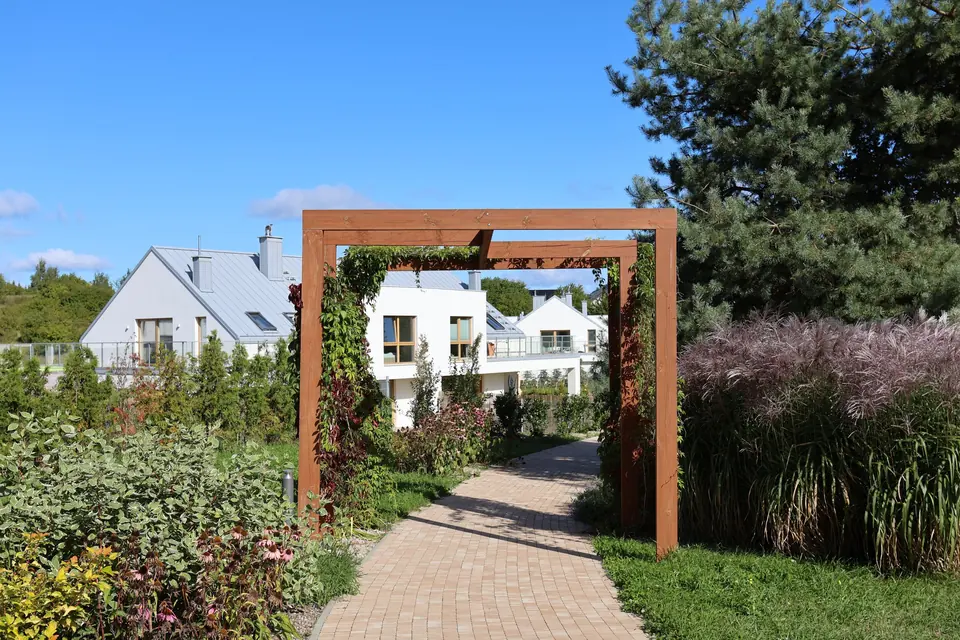 Pergola i rabaty, w tle domy Brizo Park